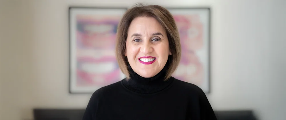 A professional photo of dentist Sharareh Khoshbin, smiling and wearing a turtleneck sweater